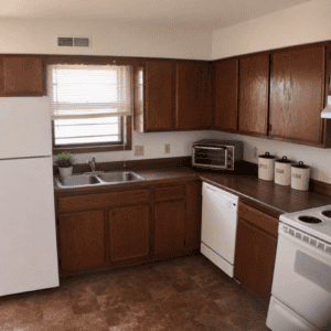 A kitchen at Westridge Apartments features brown cabinets, white appliances including a refrigerator, dishwasher, toaster oven, and stove. Enjoy a double sink under a window with blinds, and three labeled canisters neatly arranged on the counter. A kitchen at Westridge Apartments features brown cabinets, white appliances including a refrigerator, dishwasher, toaster oven, and stove. Enjoy a double sink under a window with blinds, and three labeled canisters neatly arranged on the counter.